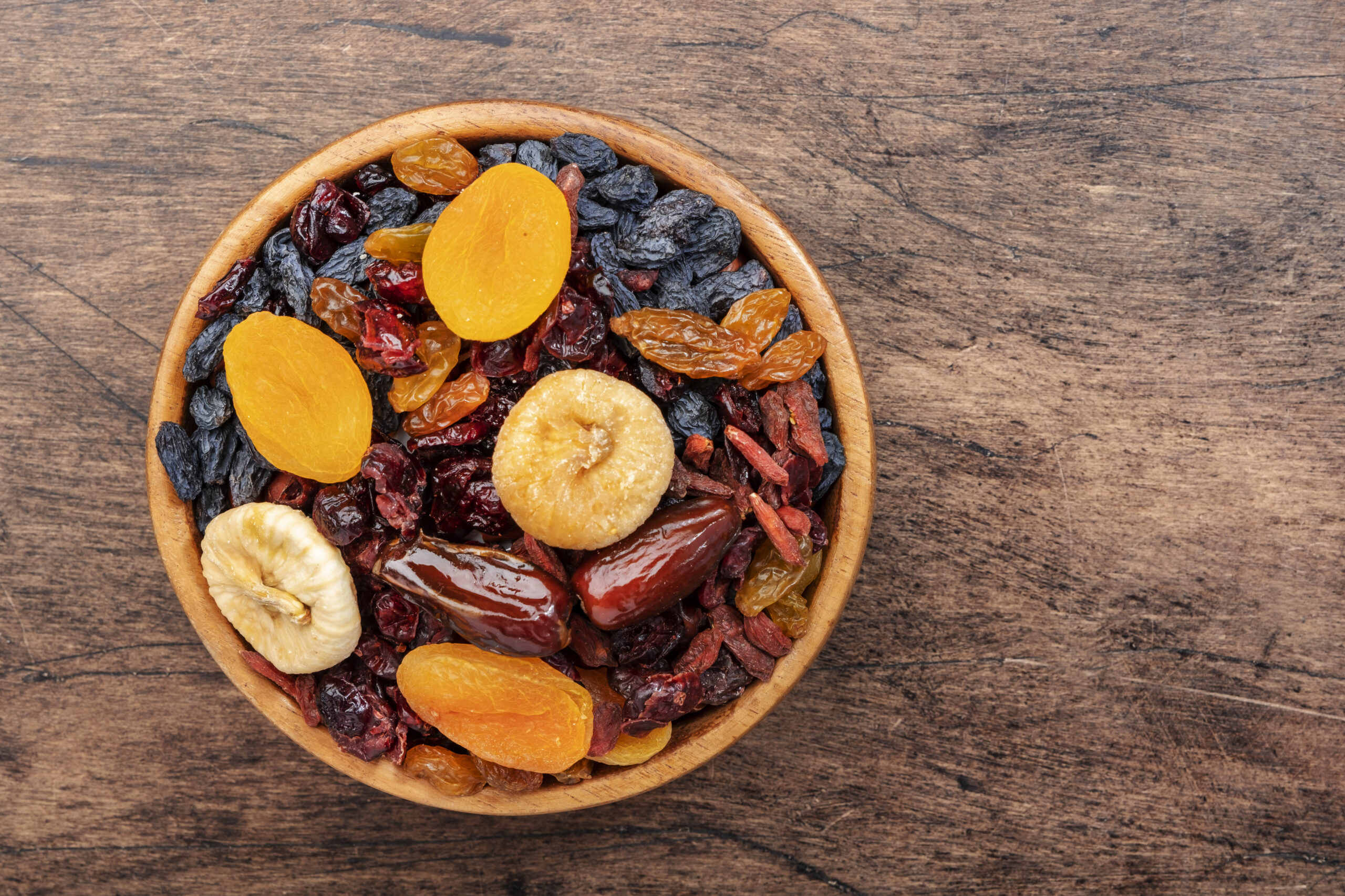Dried fruits bowl. Healthy food snack: sun dried organic mix of apricots, figs, raisins, dates and other on wooden table, top view