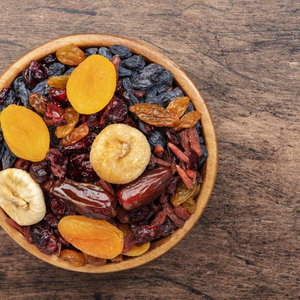 Dried fruits bowl. Healthy food snack: sun dried organic mix of apricots, figs, raisins, dates and other on wooden table, top view