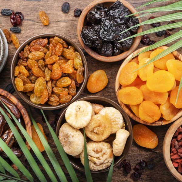 Natural Dried fruits in bowls. Healthy food snack: sun dried organic mix of apricots, figs, raisins, dates and other on wooden table, top view